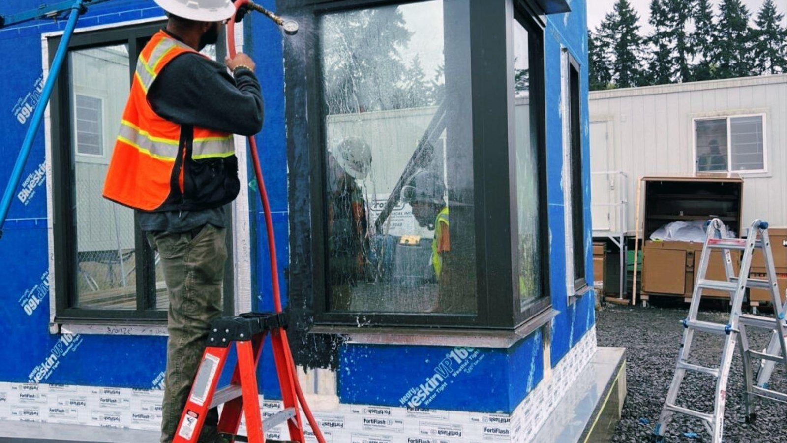 Technician sprays water on window frame to test building envelope for water penetration resistance.