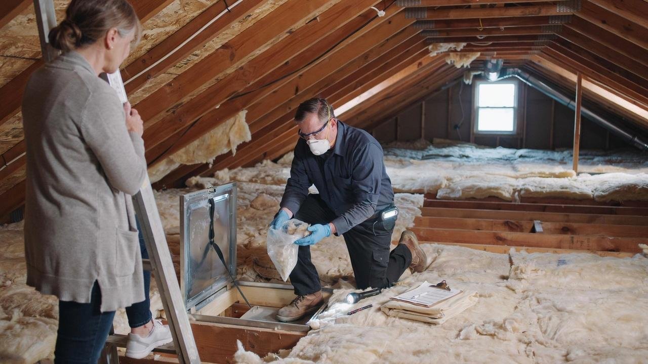 Professional inspector testing attic insulation for potential hazards before removal.