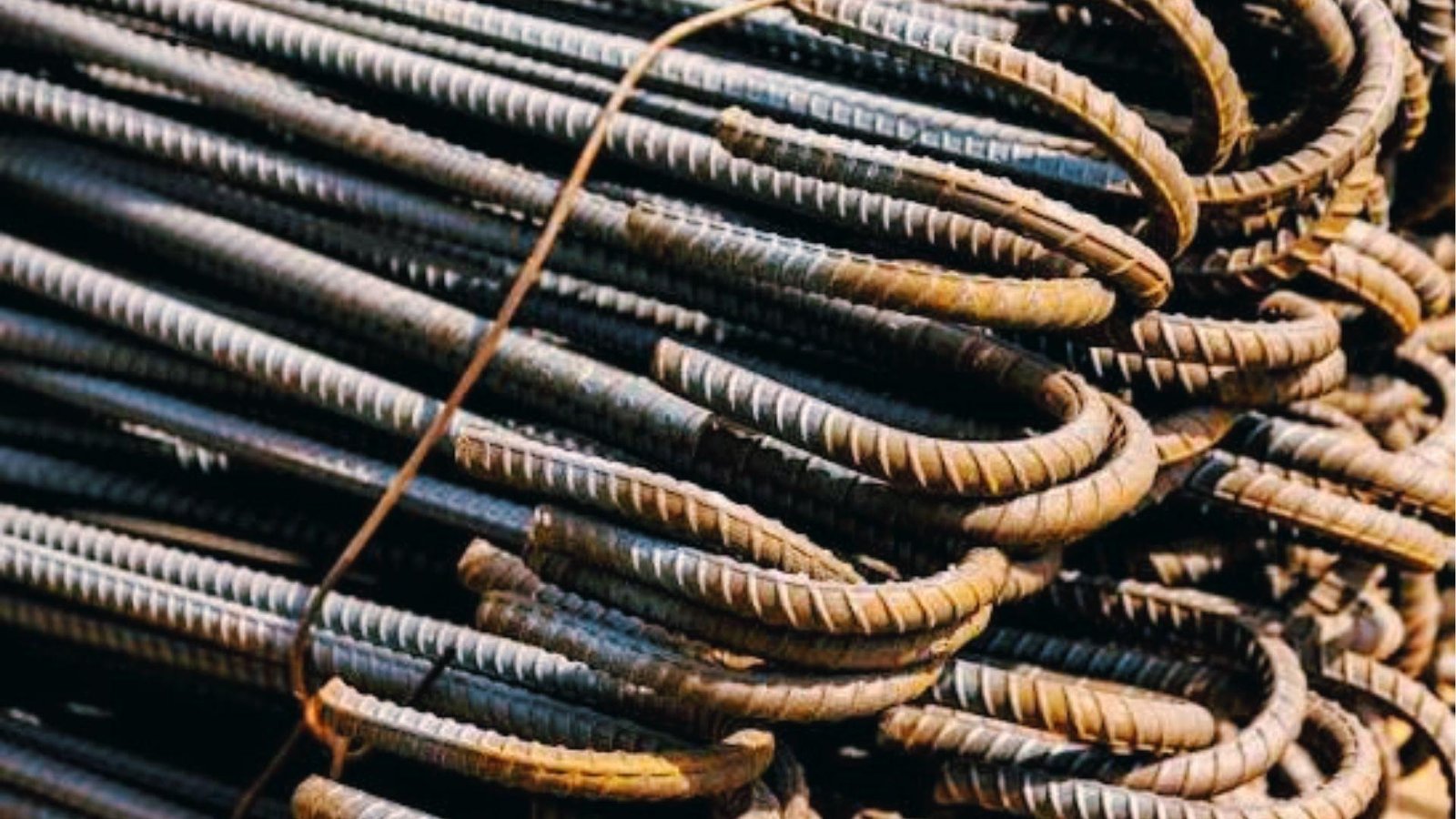 Stack of U-shaped bent rebar hooks with surface ribs, used for anchoring and reinforcing concrete beams