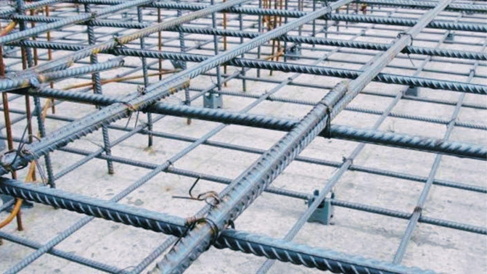 Close-up of tied steel rebar mesh with spacers showing deformed bars used to strengthen concrete slabs