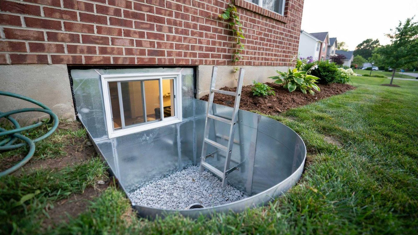 Properly installed egress window well providing basement emergency exit natural light and drainage.