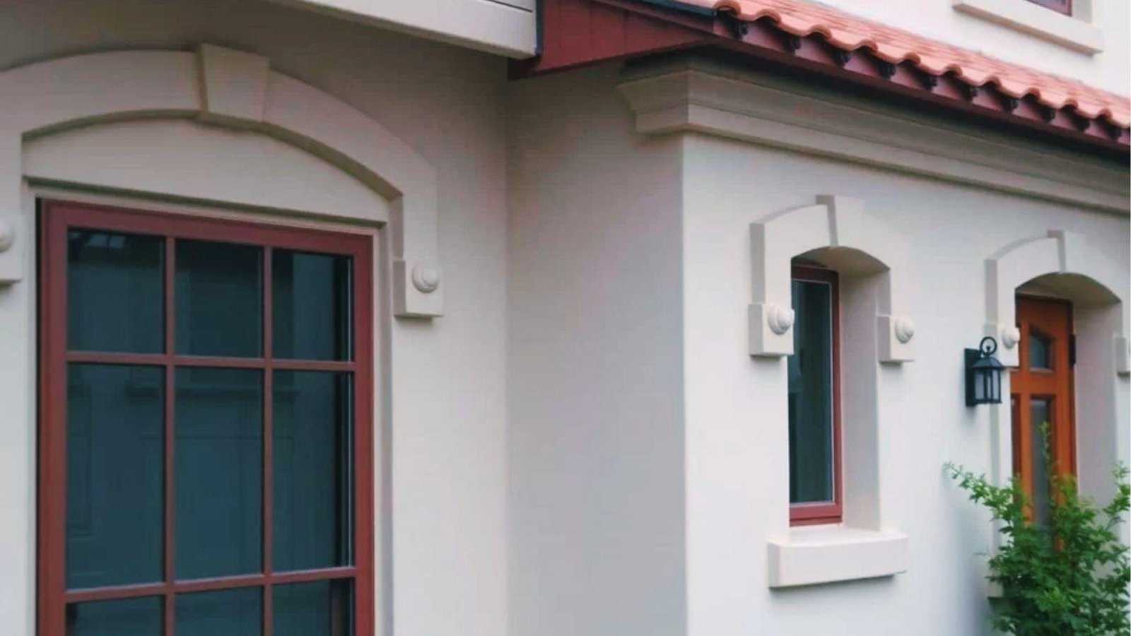 Mediterranean home with arched stucco window trim, keystones, and red framed panes.