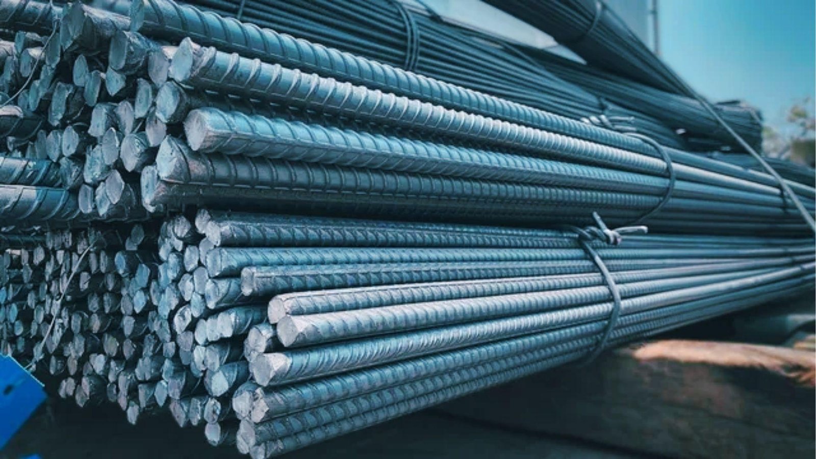 Bundles of straight deformed steel rebar stacked on site, used to add tensile strength to concrete structures