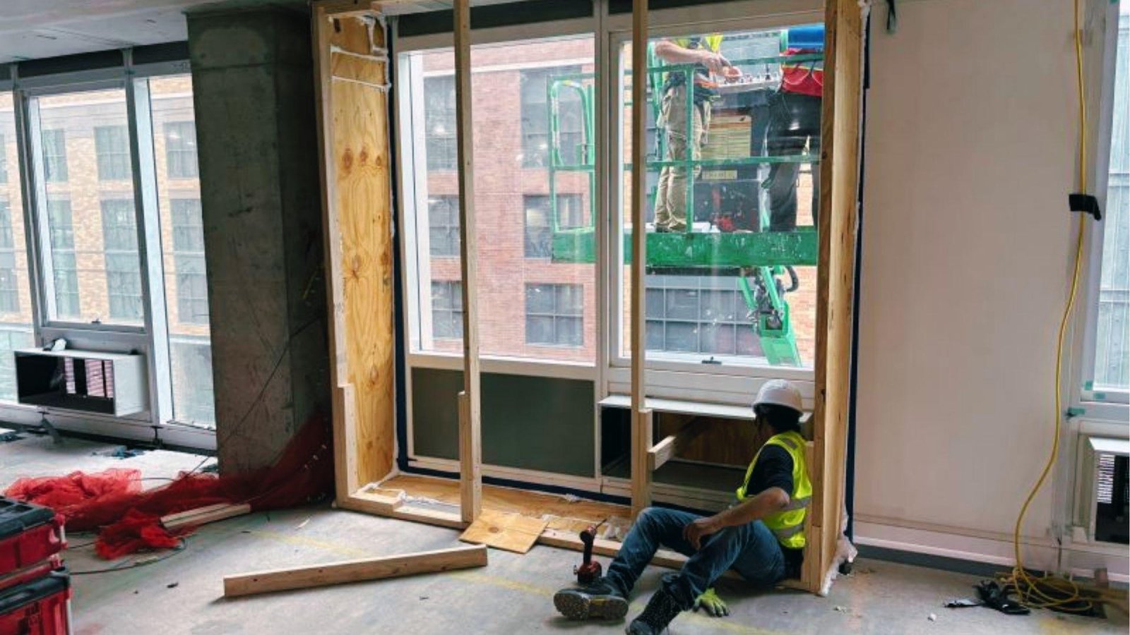 Workers prep window opening from inside for air leakage test on building envelope assembly.