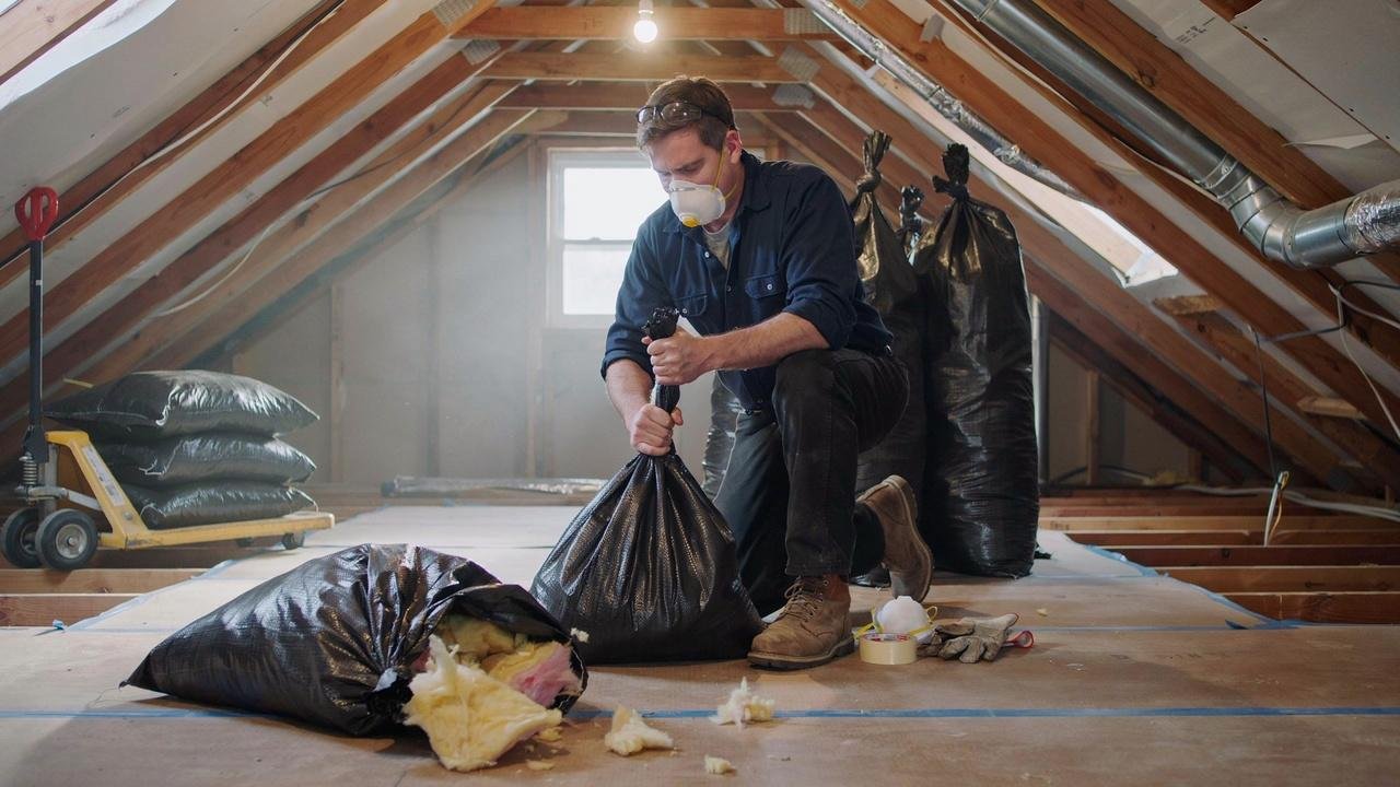 Bagging old attic insulation for disposal.